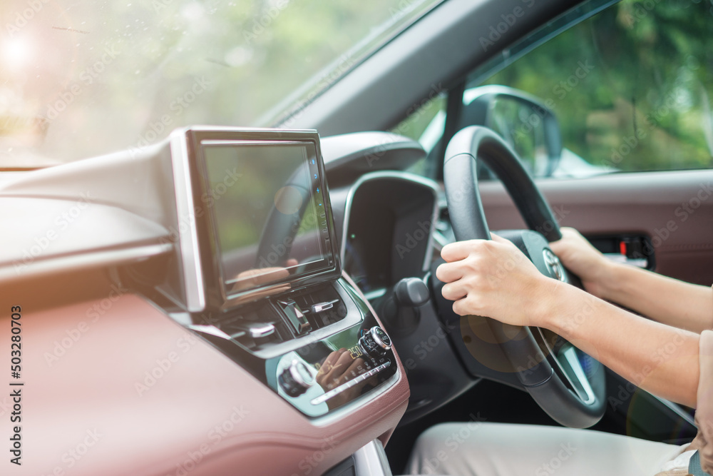 woman driver driving a car on the road, hand controlling steering wheel in electric modern automobile. Journey, trip and safety Transportation concepts