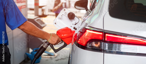 Canvas Print Man hand refuel to car, gasoline fuel nozzle in vehicle at petrol station