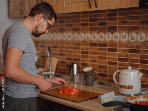 man preparing homemade tomato sauce for pizza or pasta. happy satisfied male preparing vegetarian snacks, food for dinner or party, enjoying leisure time, hobby.