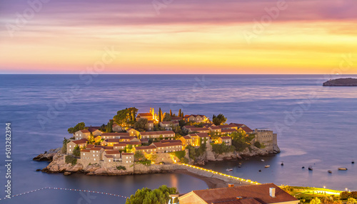 Amazing sunset view on Sveti Stefan Island City. Small islet and resort in Montenegro. Balkans, Adriatic sea, Europe. Dramatic red sky under a Saint Stefan peninsula.