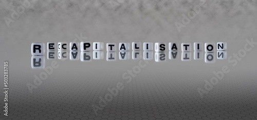 recapitalisation word or concept represented by black and white letter cubes on a grey horizon background stretching to infinity photo
