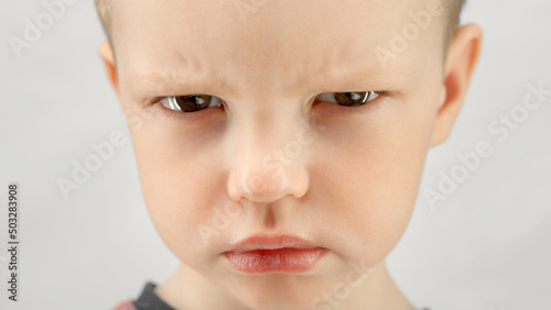 Fotografia Portrait caucasian boy 4 years old, angry child expresses emotions of discontent or anger looks at camera on white background