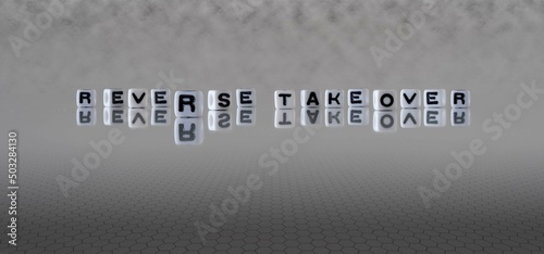 reverse takeover word or concept represented by black and white letter cubes on a grey horizon background stretching to infinity
