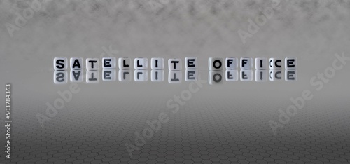 satellite office word or concept represented by black and white letter cubes on a grey horizon background stretching to infinity