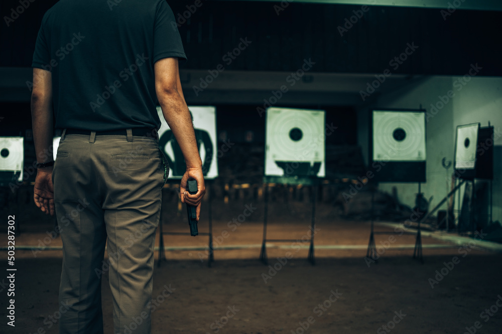 Professionals carry a 9mm pistol inside a shooting range.