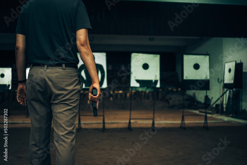 Professionals carry a 9mm pistol inside a shooting range.