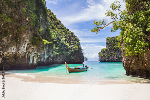Thai traditional wooden longtail boat and beautiful beach in Phuket province, Thailand.