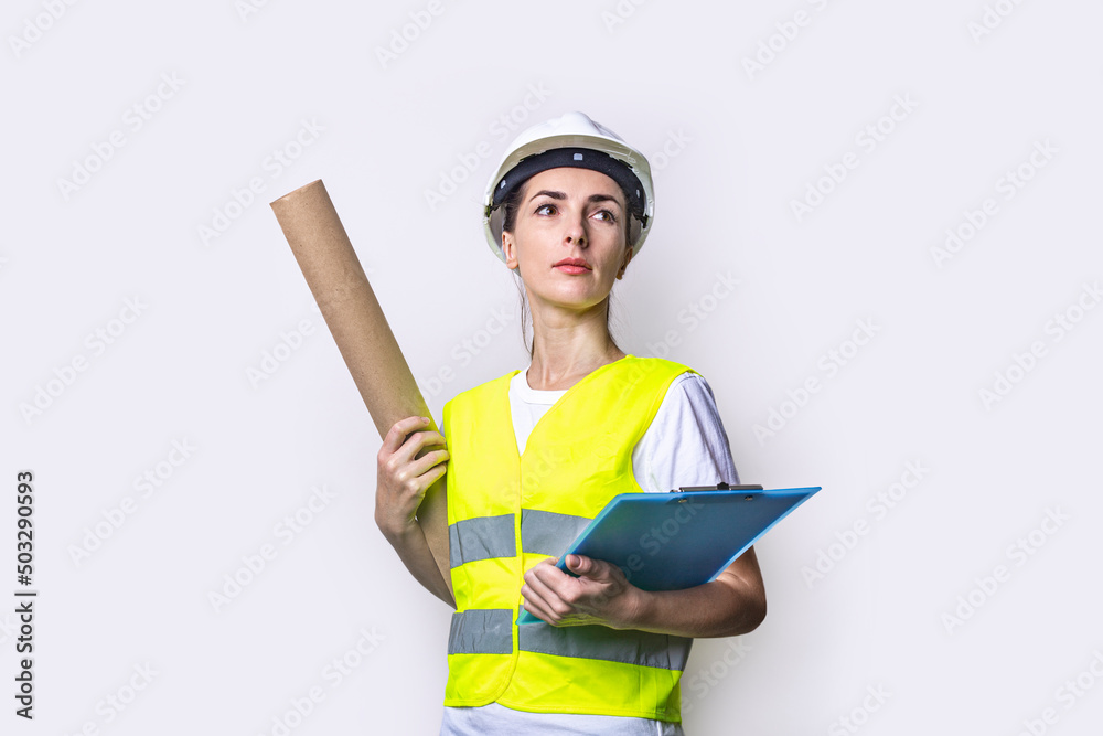 Fototapeta premium Young woman dressed in building clothes with clipboard on light background.