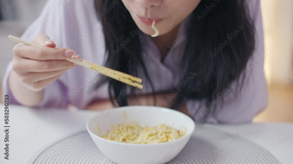 Korean woman eating noodles with chopsticks, enjoying delicious food, close-up Korean woman eating noodles with chopsticks, enjoying delicious food, close-up