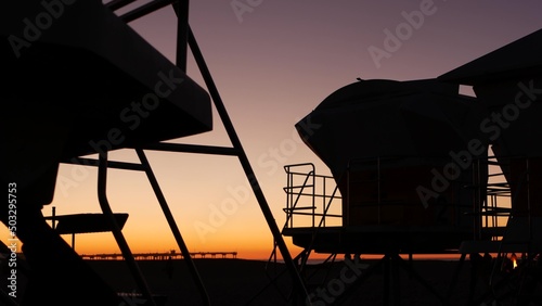 Lifeguard stand, hut or house on ocean beach after sunset, California coast, USA. Life guard tower or station silhouette in twilight dusk. Contrast beachfront watchtower for surfing safety on shore.