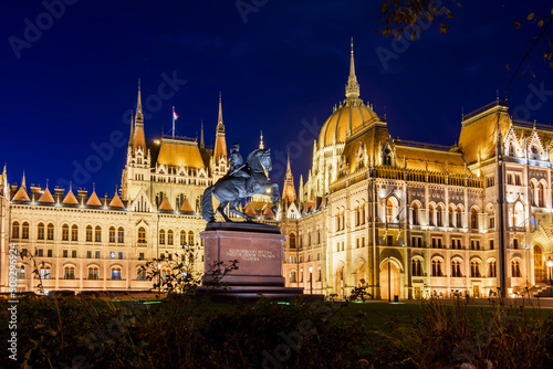 Rakoczi Ferenc monument with inscription "Ancient wounds of the noble Hungarian nation are reclaimed" in front of Hungarian Parliament at night, Budapest, Hungary © Mistervlad