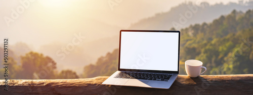 Canvas Print Empty screen laptop with cup of coffee and camera with mountain view at sunrise