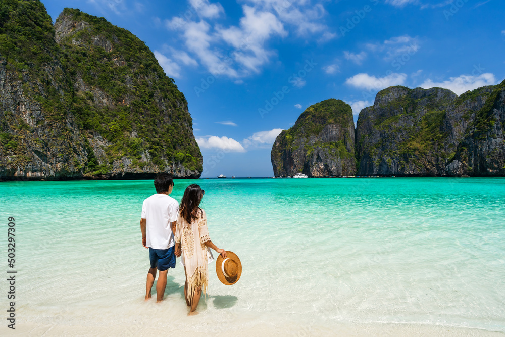 Young couple traveler relaxing and enjoying at beautiful tropical white sand beach at Maya bay in Krabi, Thailand, Summer vacation and Travel concept Young couple traveler relaxing and enjoying at beautiful tropical white sand beach at Maya bay in Krabi, Thailand, Summer vacation and Travel concept