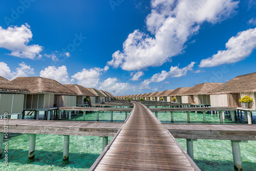 Beautiful Maldives water villa in blue lagoon and blue sky space. Panoramic summer landscape, ocean lagoon with relaxing idyllic cloudy blue sky. Exotic luxury travel background. Amazing Maldives view