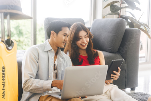 Happy smile young adult southeast asian couple using laptop for getting ready for holidays travel trip