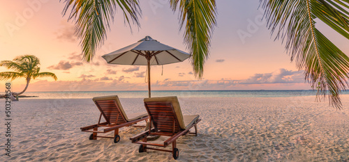 Beautiful panoramic nature. Tropical beach sunset as summer island landscape with chairs umbrella palm leaves calm sea shore  coast. Luxury travel panoramic destination banner for vacation or holiday