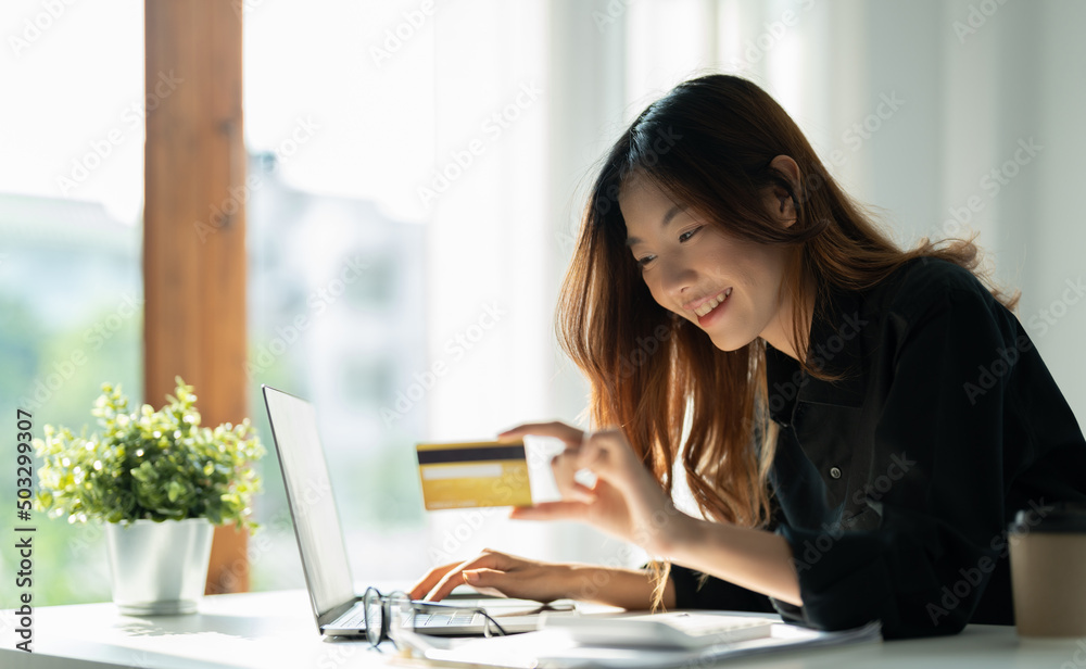 Happy woman holding credit card and using laptop computer for online shopping. Online payment shopping concept Happy woman holding credit card and using laptop computer for online shopping. Online payment shopping concept
