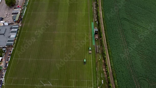 Slow aerial shot of two tractors cutting the grass at the Canterbury Rugby ground in Kent photo