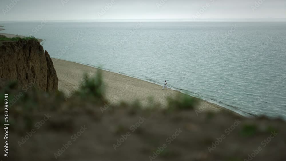 Picturesque view wild beach with unknown man training martial arts cloudy day. Picturesque view wild beach with unknown man training martial arts cloudy day.