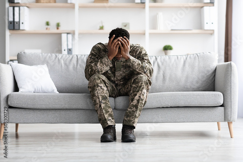 Depressed military black man covering his head with palms © Prostock-studio