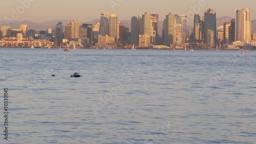 Downtown city skyline at sunset, San Diego cityscape, California coast USA. Highrise skyscrapers by bay, waterfront promenade. Urban architecture by harbor. Seamless looped cinemagraph. Shelter island © Dogora Sun
