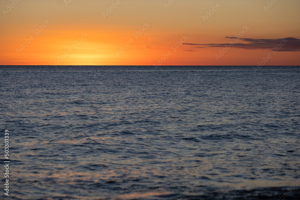 Sunset on the Caribbean coast in the Dominican Republic.Orange sunset sky with a cloud and a calm sea surface.Tourism, travel, recreation, concepts background.Beautiful scenery of the sea coast