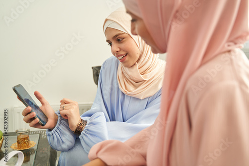Muslim women watching video on smartphone at home