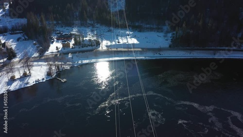 Beautiful clip above high voltage power lines from Nore powerplant and over mountaintop - Forward moving aerial with tilt up revealing bright sun - Illustrating transportation of electricity Norway photo