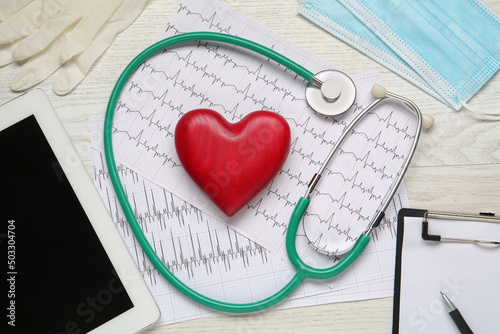 Flat lay composition with stethoscope and red heart on white wooden table. Cardiology concept photo