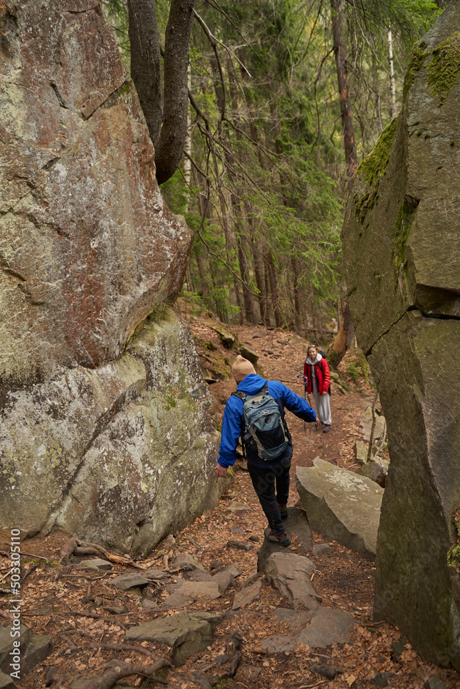 Female waiting for hiking partner to get down from boulder Female waiting for hiking partner to get down from boulder