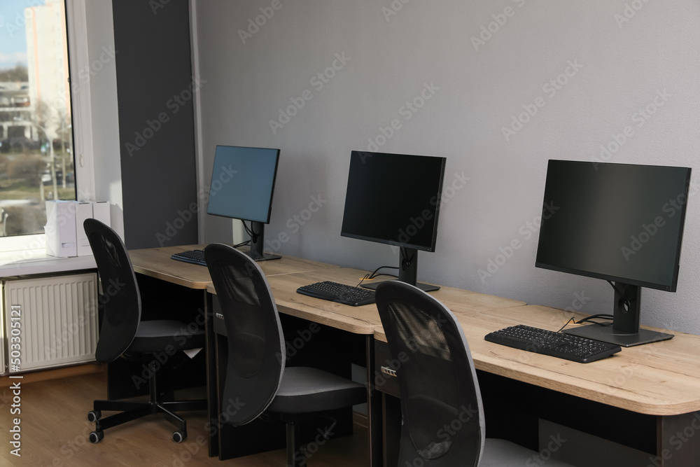 Open office interior. Modern workplaces with computers near light grey wall