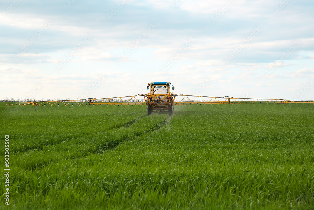 Tractor spraying pesticide in field on spring day. Agricultural industry Tractor spraying pesticide in field on spring day. Agricultural industry