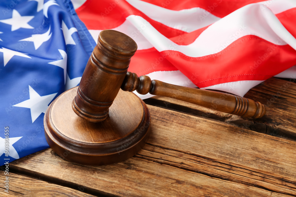 Wooden gavel and American flag on table
