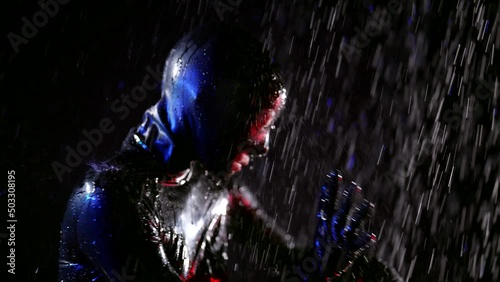 Close-up of a head fetish game of a woman in a black leather helmet with water jets on a dark background