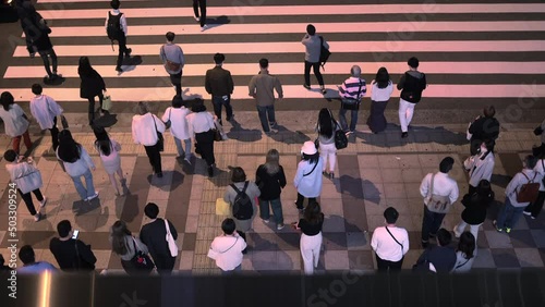 Overhead view of pedestrians crossing large crosswalk at night in slow motion photo
