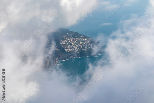 Panoramic view from Monte Comune on the coastal town Positano appearing from clouds. Magical hiking above thick fog in Lattari Mountains, Apennines, Amalfi Coast, Campania, Italy, Europe. Misty vibes