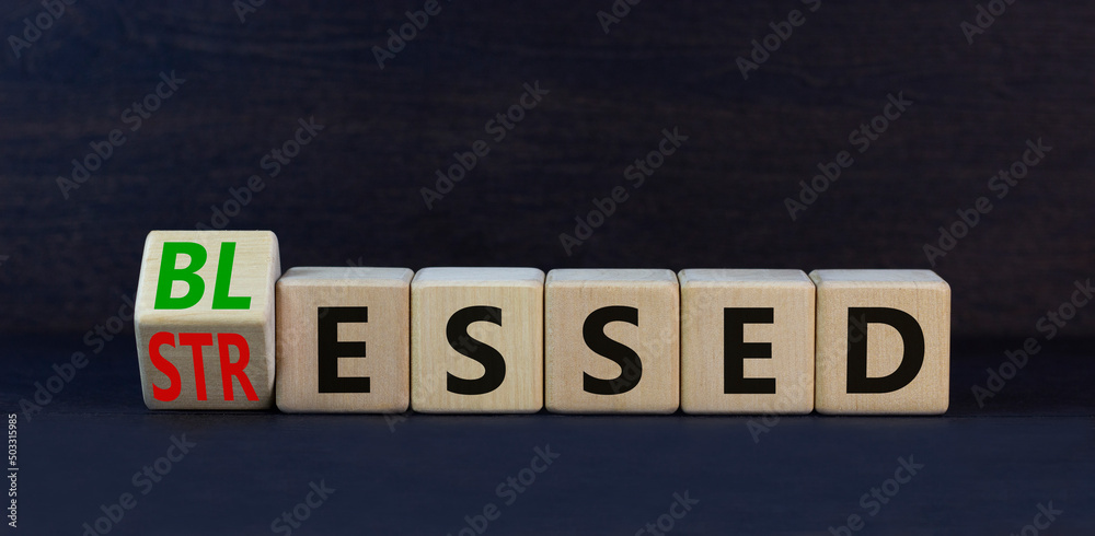 Blessed or stressed symbol. Turned wooden cubes and changed the concept word Stressed to Blessed. Beautiful black table black background. Business blessed or stressed concept. Copy space.
