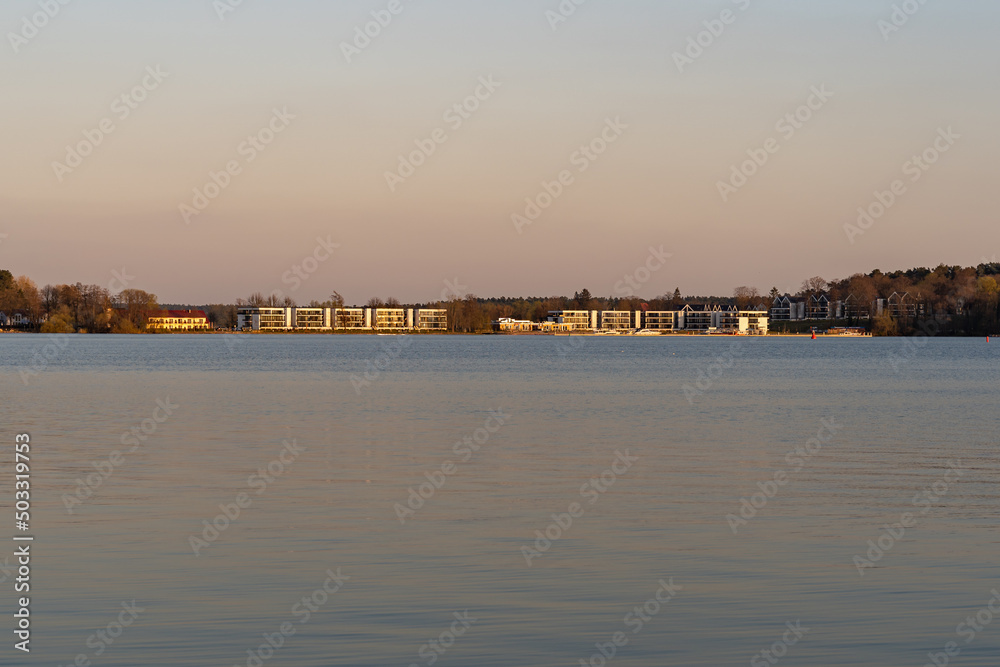 Luxury hotel building at a the waterfront of a calm lake. Sunset landscape with modern architecture. The beautiful nature is a travel destination for many tourists in Germany.
