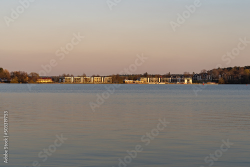 Luxury hotel building at a the waterfront of a calm lake. Sunset landscape with modern architecture. The beautiful nature is a travel destination for many tourists in Germany.