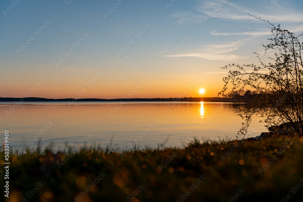 Lake Müritz when the sun is going down. Natural landscape during spring season. Beautiful sunset scenery with reflections in the water. Orange sunlight over the horizon.