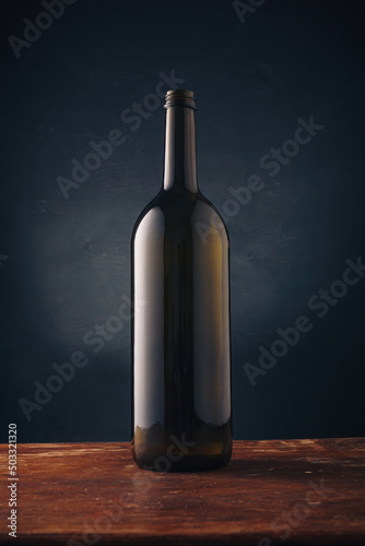 Wine bottle without label, no brand mockup on dark wooden background. Alcohol drink, vertical close up shot photo