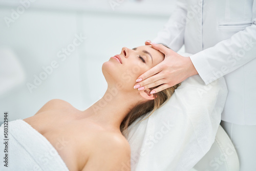 Young nice woman having face massage in spa