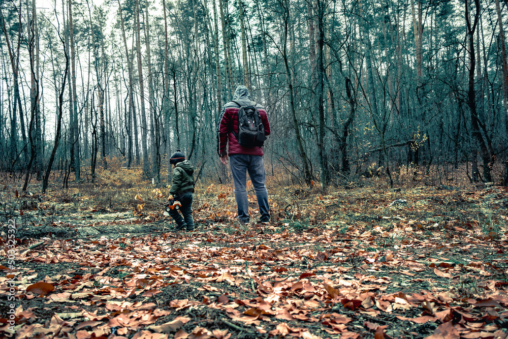 A man and a little boy are looking for a way in the forest. A father and son are walking through a dense forest