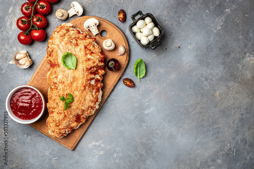 Calzone pizza with tomatoes, mozzarella, mushrooms and fresh basil, italian calzone vegetarian pizza, banner, menu, recipe place for text, top view