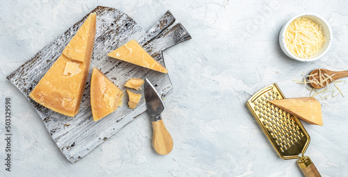 Pieces of parmigiano reggiano or parmesan cheese. Sliced and grated parmesan cheese with rosemary on a light table, Long banner format. top view photo