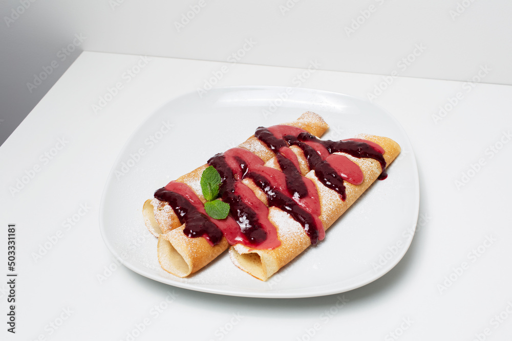 Vegan dessert. Rolled thin pancakes with berry cream topping, on the white. Vegan dessert. Rolled thin pancakes with berry cream topping, on the white.