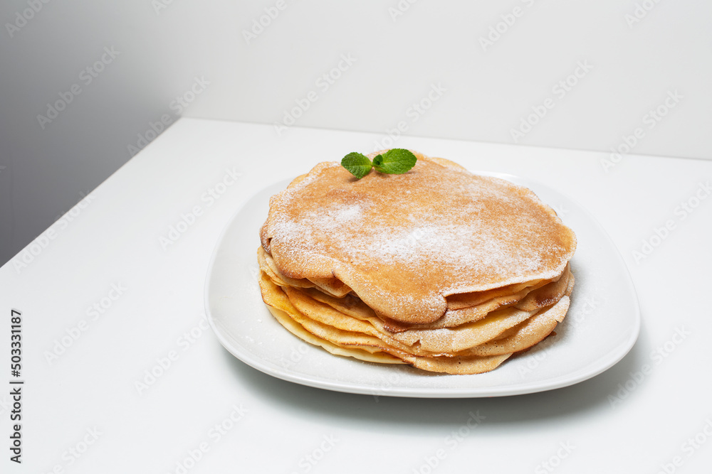 Picture of vegan thin pancakes, on the white plate, decorated with mint leaf. Picture of vegan thin pancakes, on the white plate, decorated with mint leaf.