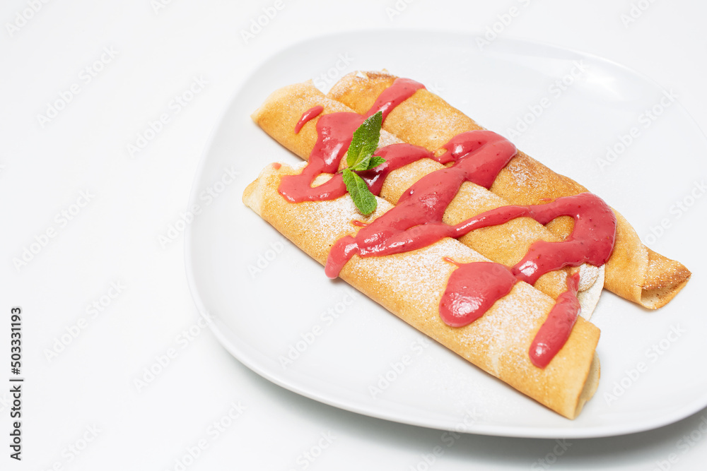Vegan dessert. Rolled pancakes with strawberry cream topping, on white. Vegan dessert. Rolled pancakes with strawberry cream topping, on white.