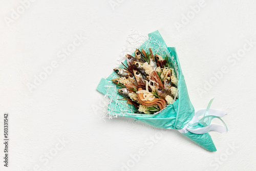 Turquoise bouquet made of dried fish and snacks on a white background