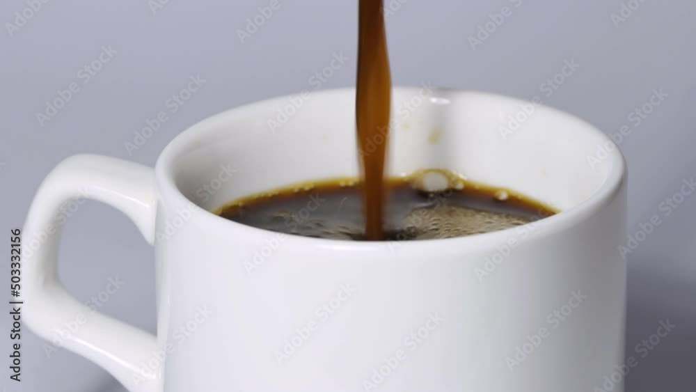 Pouring black coffee into a white cup. Top view of coffee poured into a cup with foam. Pouring black coffee into a white cup. Top view of coffee poured into a cup with foam.